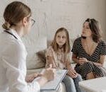 A mother and daughter consult with a doctor during a medical appointment indoors.